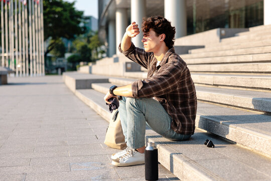Man on steps shields eyes and holding wet towel