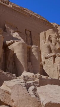 Close-up of giant Ramesses II colossi carved into rock facade at Abu Simbel temple, Egypt. Dramatic upward view of ancient sandstone pharaoh statues. Travel and history.
