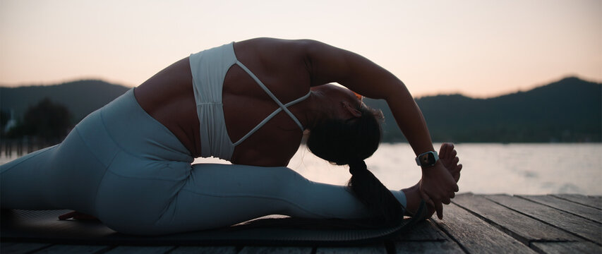 Practicing yoga and stretching at sunset time by lake, finding peace