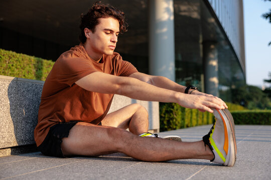 Man stretching leg in running shoes outdoors.