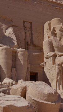 Close-up of giant Ramesses II colossi carved into rock facade at Abu Simbel temple, Egypt. Dramatic upward view of ancient sandstone pharaoh statues. Travel and history.