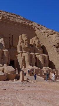 Close-up of giant Ramesses II colossi carved into rock facade at Abu Simbel temple, Egypt. Dramatic upward view of ancient sandstone pharaoh statues. Travel and history.