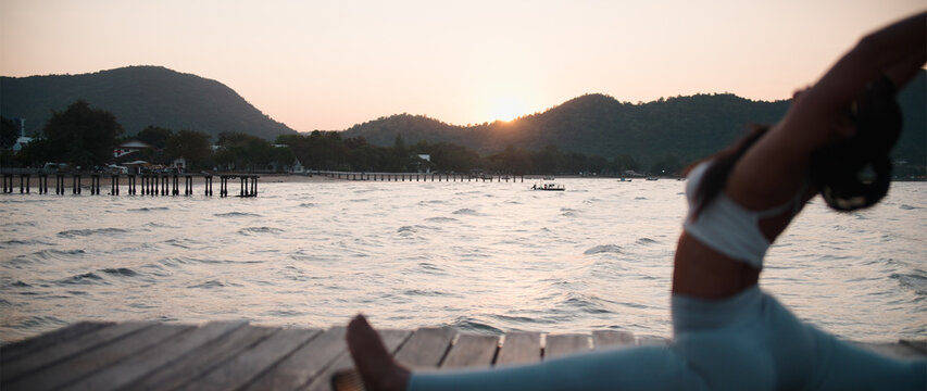 Fitness professional stretching on pier during peaceful sunset 