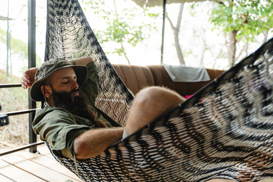 Man sleeping in hammock on outdoor porch enjoying siesta