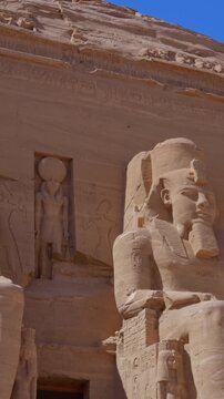 Close-up of giant Ramesses II colossi carved into rock facade at Abu Simbel temple, Egypt. Dramatic upward view of ancient sandstone pharaoh statues. Travel and history.