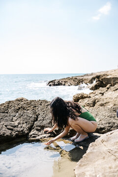 Woman crouching by tidepool
