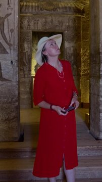 Woman in a red dress examines  the temple in Abu Simbel, Egypt.