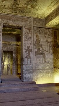 Atmospheric interior of Small Temple of Nefertari at Abu Simbel with carved gods reliefs, hieroglyphics and warm golden lighting, Egypt. Rare inside view for history content.