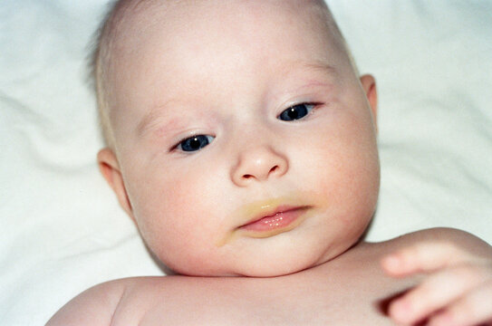 Baby with blue eyes lying on a white surface