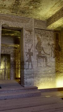 Atmospheric interior of Small Temple of Nefertari at Abu Simbel with carved gods reliefs, hieroglyphics and warm golden lighting, Egypt. Rare inside view for history content.