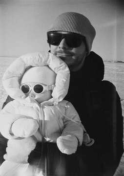 Man holds baby in winter clothing on a snowy day
