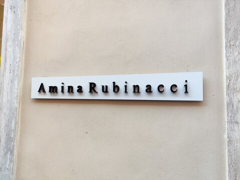 Rome, Italy - June 03, 2026: Amina Rubinacci store sign displayed on a beige wall, showcasing elegant typography and branding in a retail environment