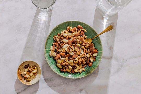 Nuts on a green plate with a small bowl next to it.  