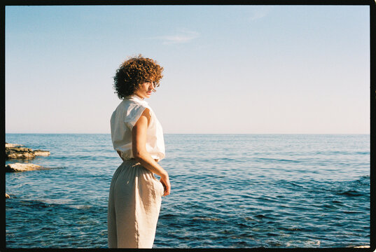 Woman with curly hair finding peace by sea