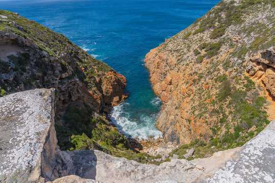 Small ocean cove between high colorful sea cliffs