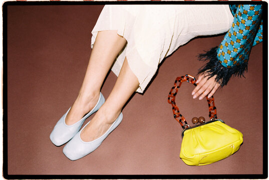 Legs with light blue ballet flats and a yellow handbag