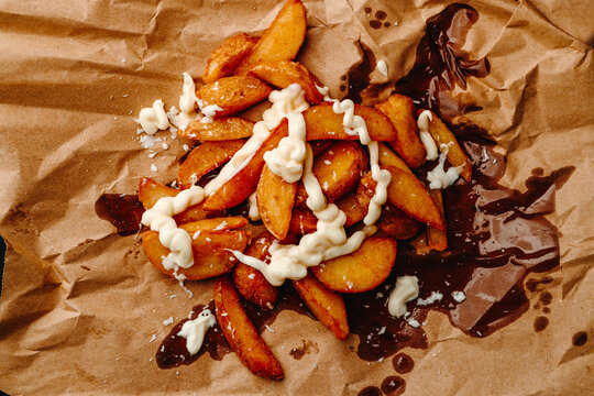 potato wedges with mayonnaise on brown paper
