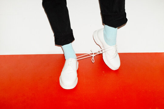 Conceptual image of person wearing shoes and having a knot in the lace