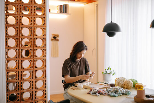 Woman weaving wool on a wooden frame loom 