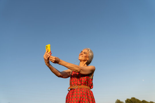 Senior woman using phone blue sky