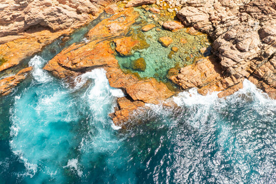 Natural rockpool amongst by colorful boulders along a rugged coastline