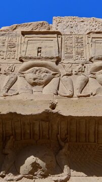 Upward view of ornate floral capitals on Ptolemaic columns at Philae Temple, Aswan Egypt. Elegant ancient architecture against vivid blue sky. Travel and history content.