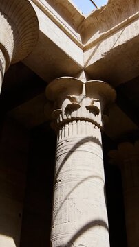 Ancient Egyptian Philae Temple. interior with massive carved stone columns covered in hieroglyphs, low angle view highlighting detailed reliefs and architectural grandeur.