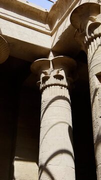 Ancient Egyptian Philae Temple. with massive carved stone columns covered in hieroglyphs, low angle view highlighting detailed reliefs and architectural grandeur.