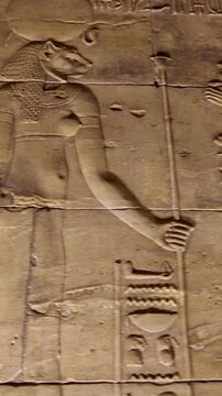 Detailed reliefs of ancient Egyptian deities and hieroglyphs carved on the walls of the Philae Temple. Egypt.