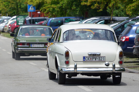 Rear view of a vintage white Volvo Amazon and green Mercedes-Benz W123 sedan driving in a convoy on the street during a classic car meeting in Palic, Serbia on June 6, 2026