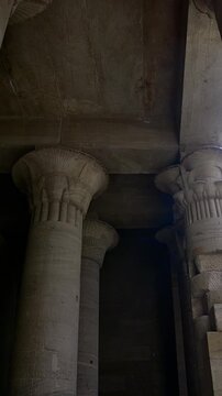 Ancient Egyptian Philae Temple. interior with massive carved stone columns covered in hieroglyphs, low angle view highlighting detailed reliefs and architectural grandeur.