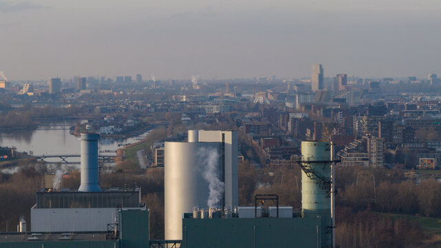 Aerial view of Vattenfall Elektriciteitscentrale Diemen power plant with industrial chimneys emitting smoke, overlooking the urban cityscape and river, Diemen, Noord-Holland, Netherlands.