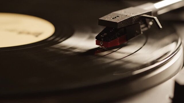 A close view of a needle playing a black vinyl record
