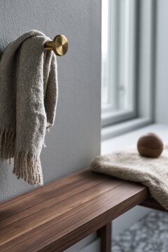 Soft woven throw hanging on brass wall hook above walnut bench in minimalist interior
