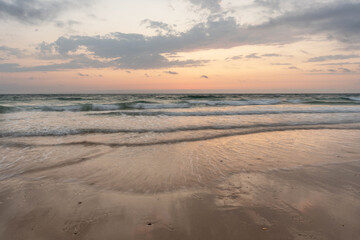 Obraz premium Sunset on the beach with moving waves 