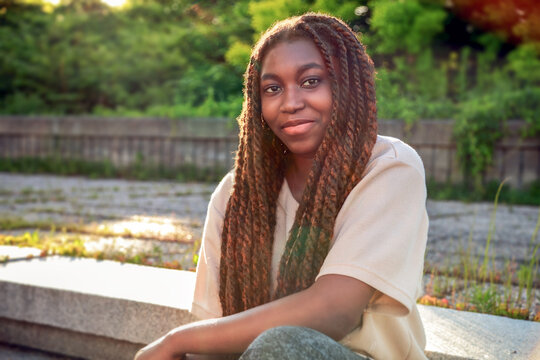 Fabulous outdoor portrait of a young Black university student sitting on sunlit campus steps