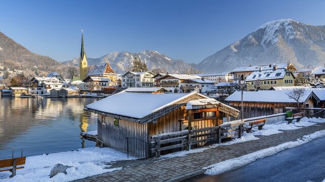 Snowy winter view of Malerwinkel with boathouses, parish church and Wallberg 1722m, Rottach-Egern, Tegernsee, Tegernsee valley, Bavarian Alps, Upper Bavaria, Bavaria, Germany