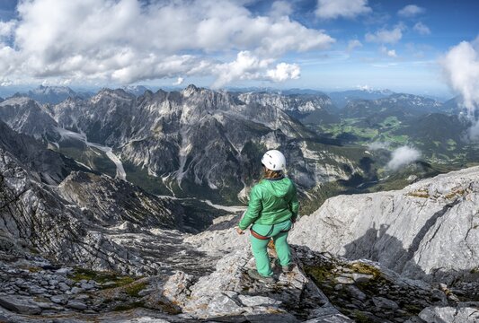Hiker with helmet at the summit of the Watzmann, view over mountains, mountain range Hochkalterstock with Blaueisspitze and Hochkalter, hiking trail to the Watzmann, Watzmann crossing, Berchtesgaden, Bavaria, Germany