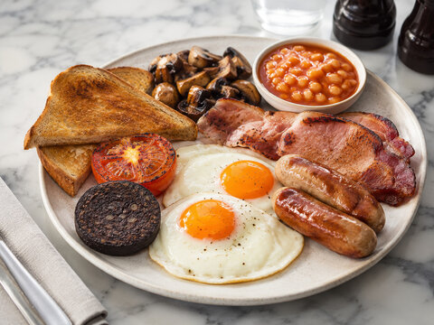 Desayuno con huevos, salchichas y pan tostado en un plato