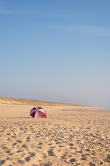 A parasol offering protection from the sun and wind on a beach in Les Landes, New Aquitaine. © Néstor MN