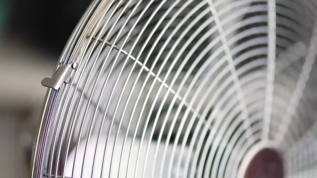 Close-up on electric cooling fan in apartment during summer heatwave