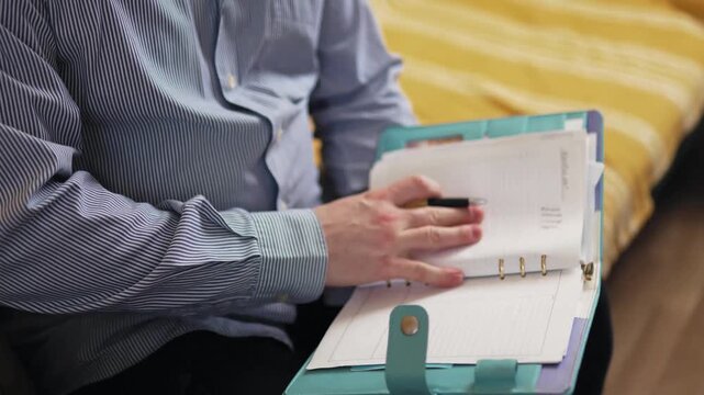 oung man planning his schedule in a planner on a sofa at home