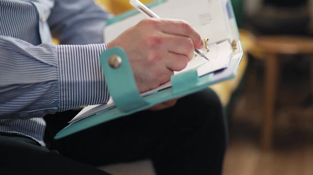 oung man planning his schedule in a planner on a sofa at home