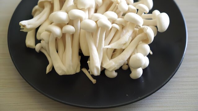 Fresh enoki mushrooms on black plate in a natural setting