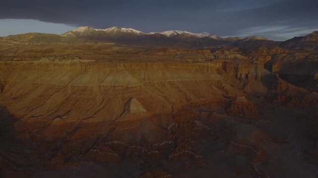 An aerial flyover sandstone rock formation and cliffs near the Henry Mountains at sunrise, Utah