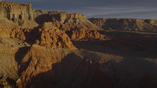 An aerial flyover sandstone rock formation and cliffs near the Henry Mountains at sunrise, Utah