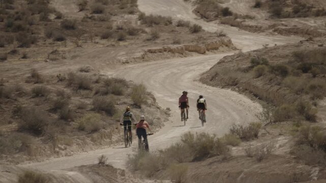 A group of four woman riding mountain bikes on a rural dirt road in the dessert, St. George, Utah