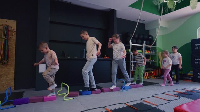 Children perform a balance and coordination exercise in a fitness class. Young students are actively engaged in a physical activity course.