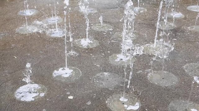 Water jets splashing from a floor fountain in slow motion