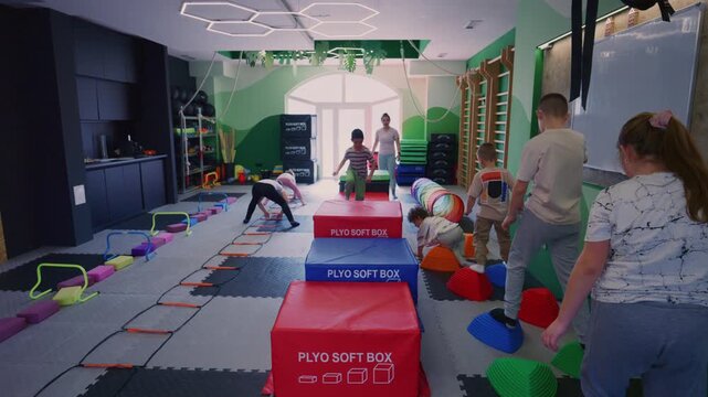 Young children engage in fitness activities, navigating an obstacle course. Kids exercise and develop physical skills in a fun, active gym.
